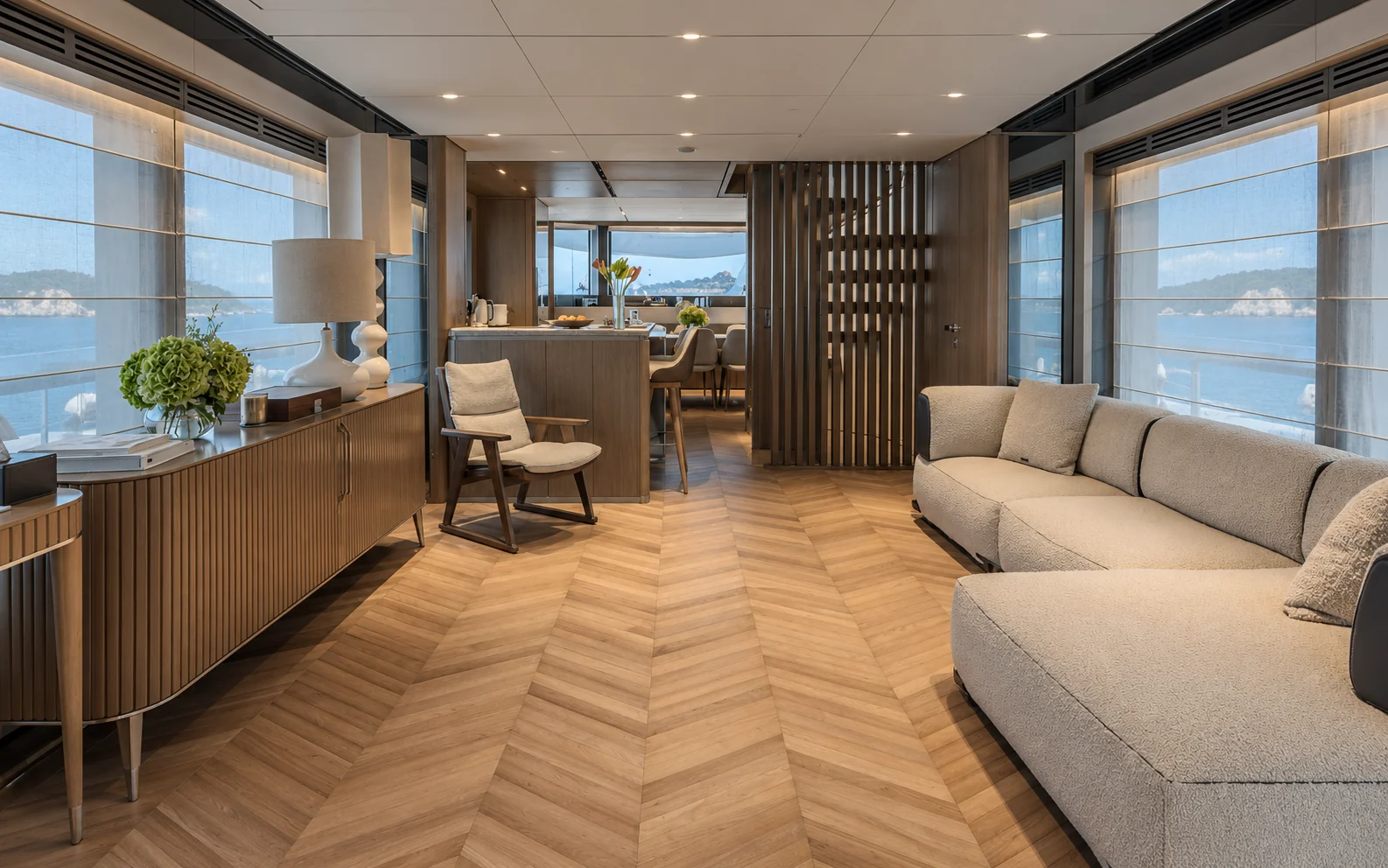 Main saloon with chevron oak floor, L-shaped sofa and fluted oak sideboard